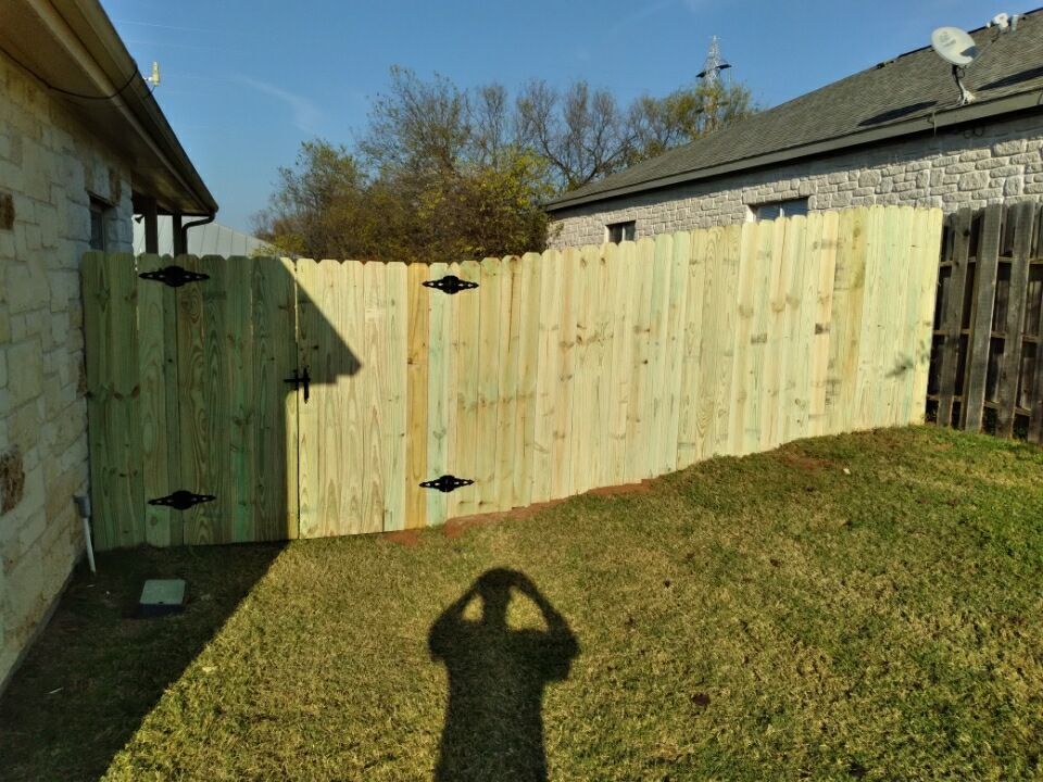 A wooden fence with a gate in the backyard of a house.