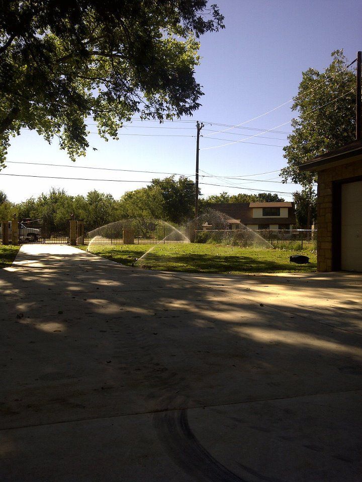 A lawn sprinkler is spraying water in a driveway