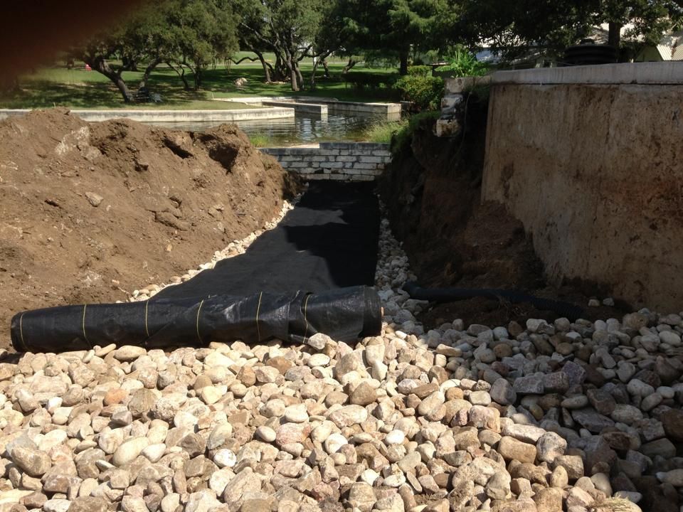 A pile of rocks is being covered with a black tarp