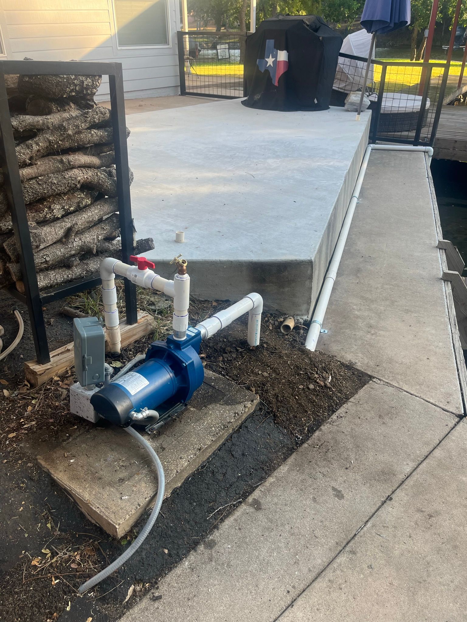 A water pump is sitting on a sidewalk next to a dock.