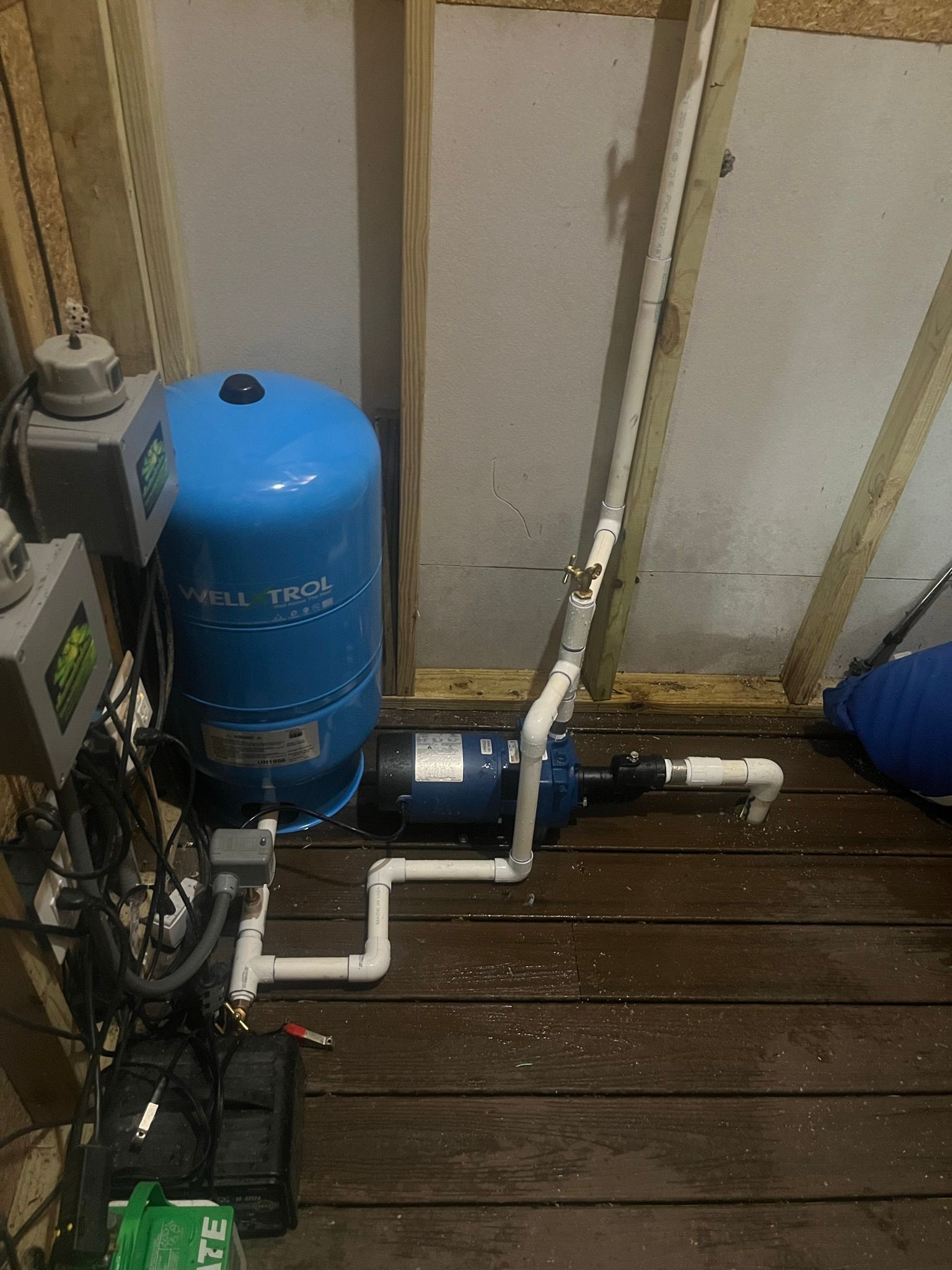 A water pump is sitting on a wooden floor in a room.