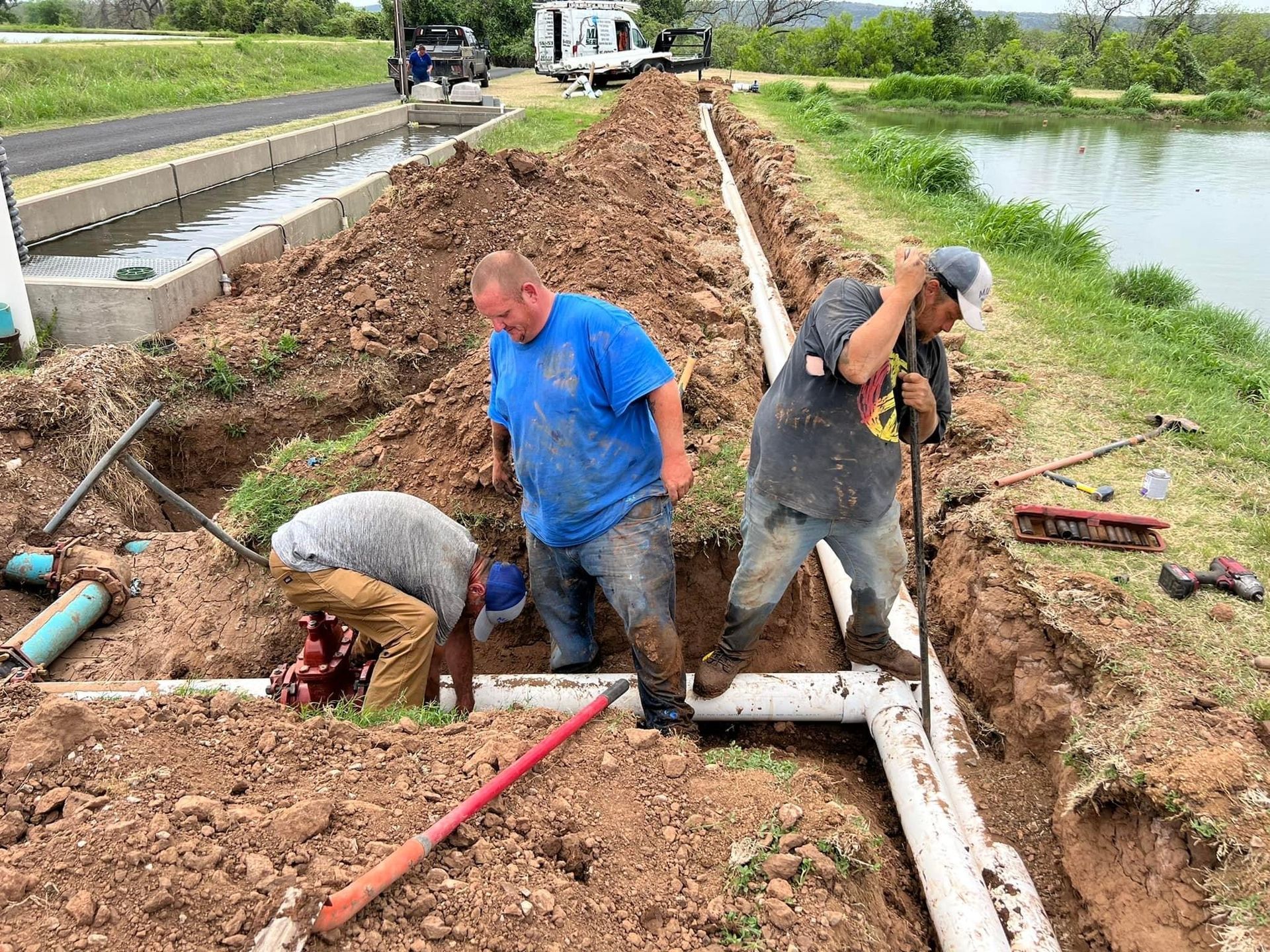A group of men are working on a pipe line in the dirt.