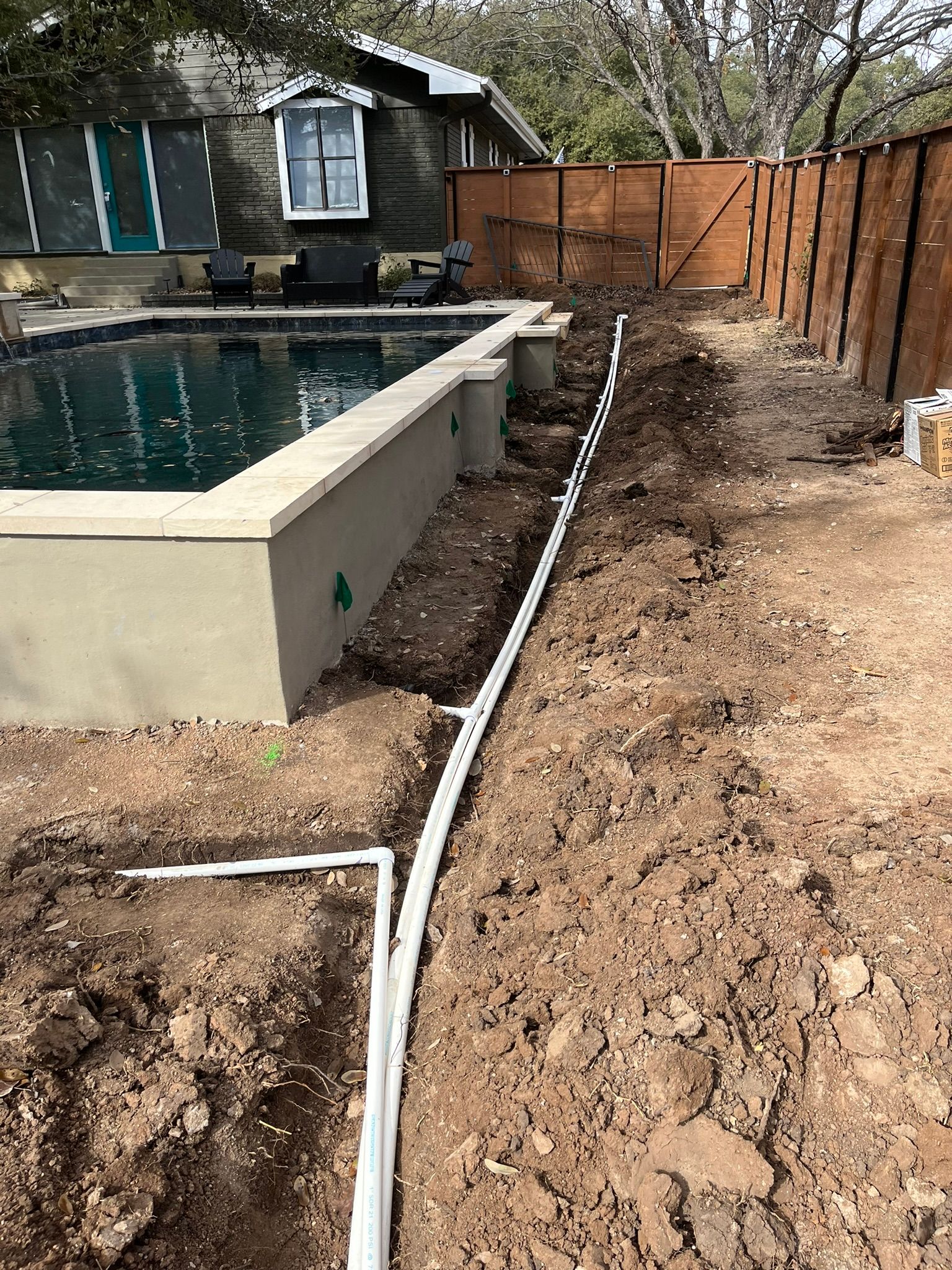 A swimming pool is being built in the backyard of a house.