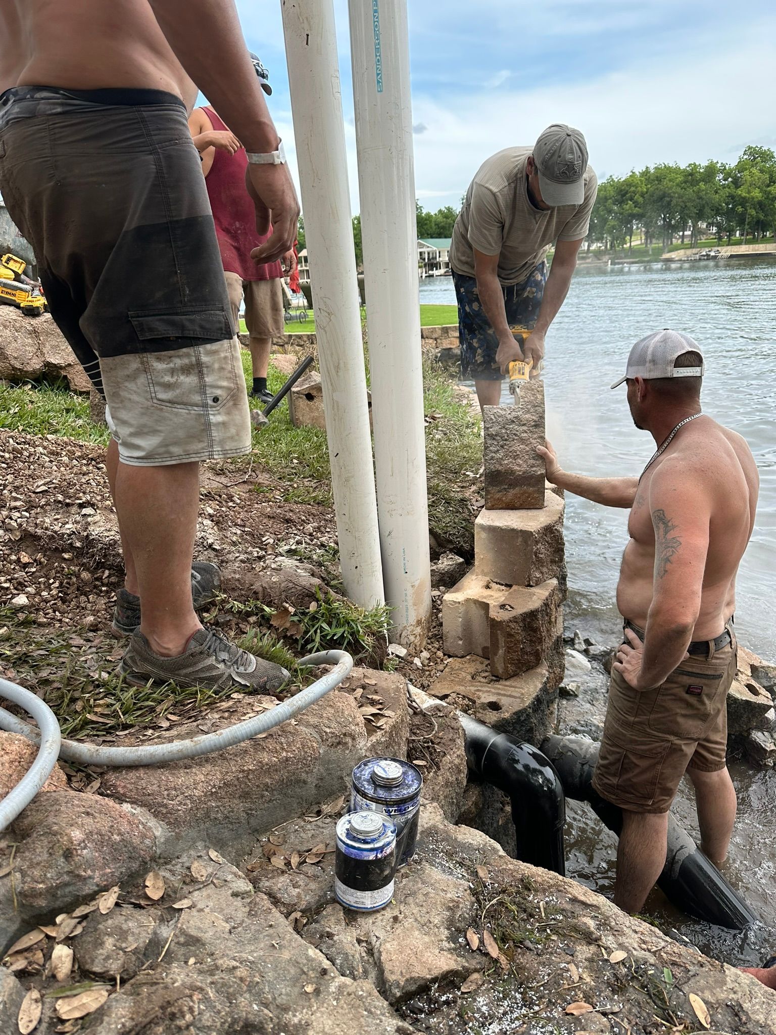 A group of men are standing next to a body of water.