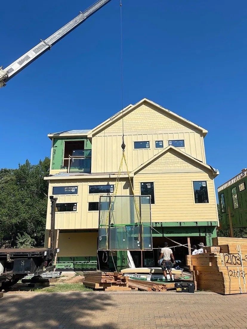 A large yellow house is being built with a crane in the background.