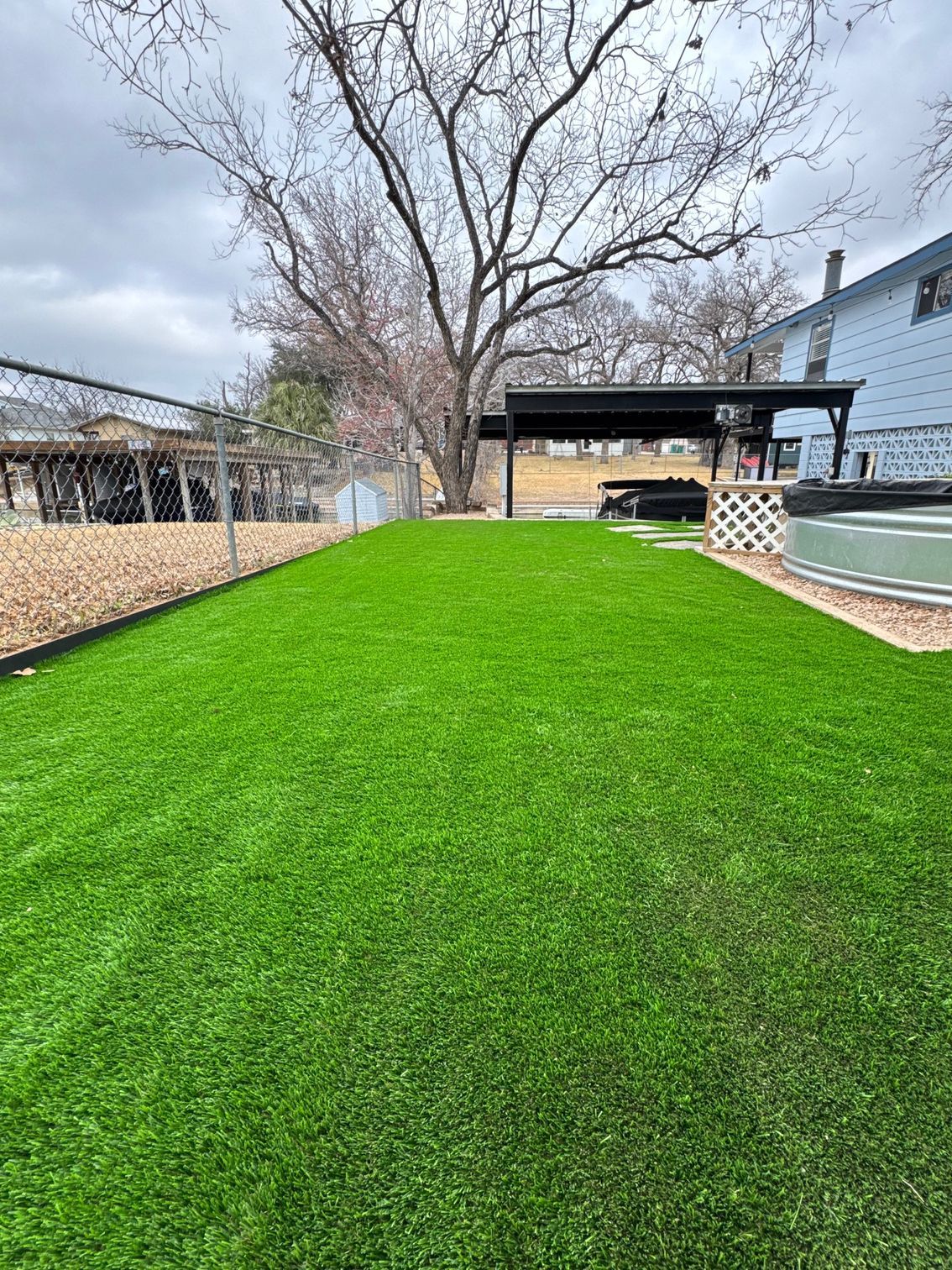 A backyard with a lot of green grass and a pool.