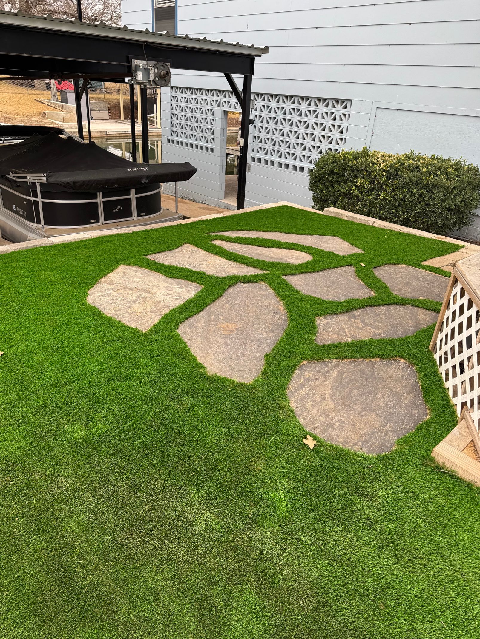 A lush green lawn with stepping stones and a boat in the background.