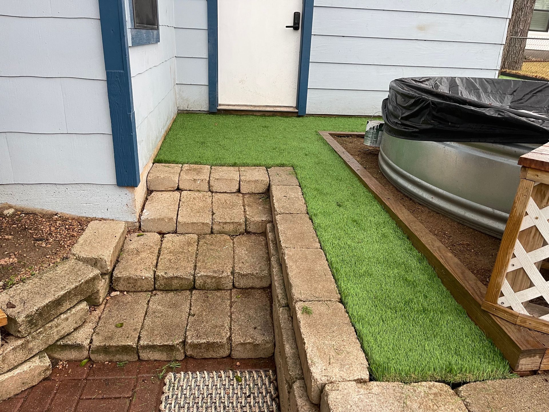 A brick walkway leading to a house with a hot tub in the background.