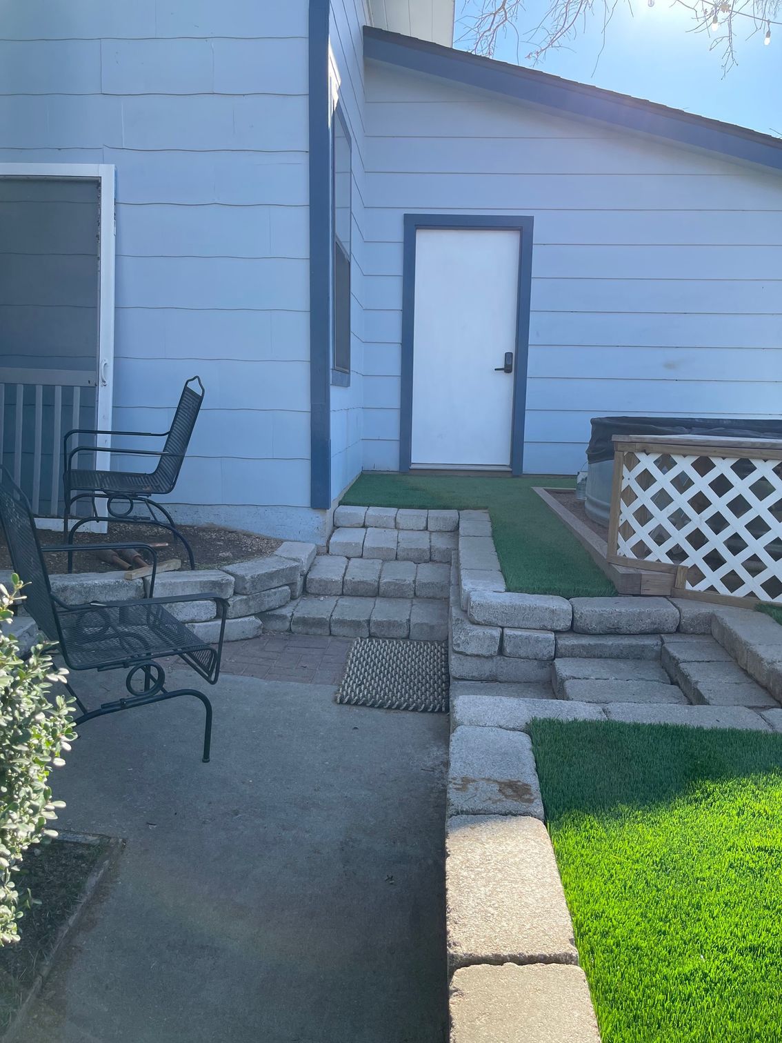 A blue house with a white door and a patio with chairs.