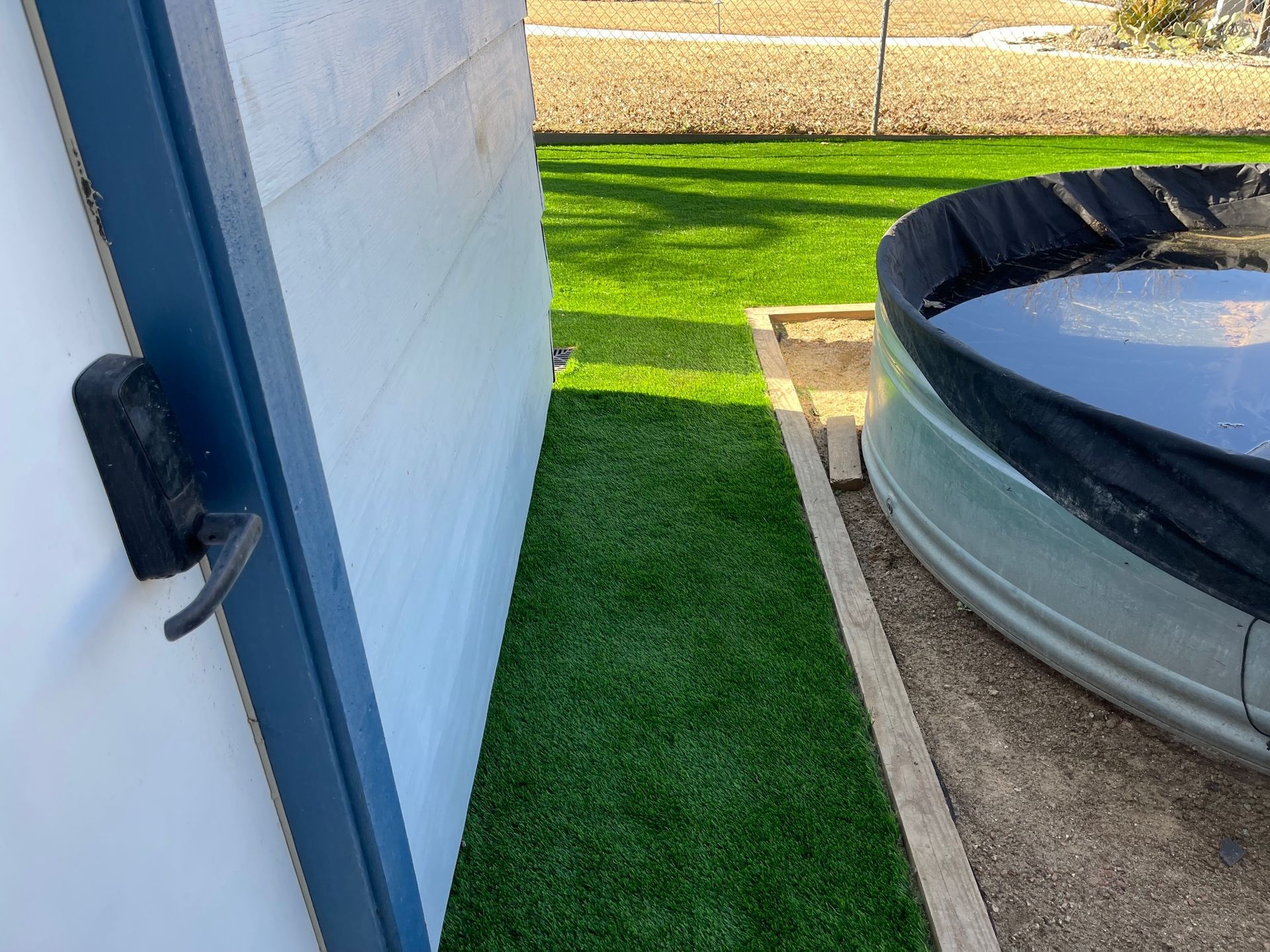 A white building with a blue door and a pool in the backyard.