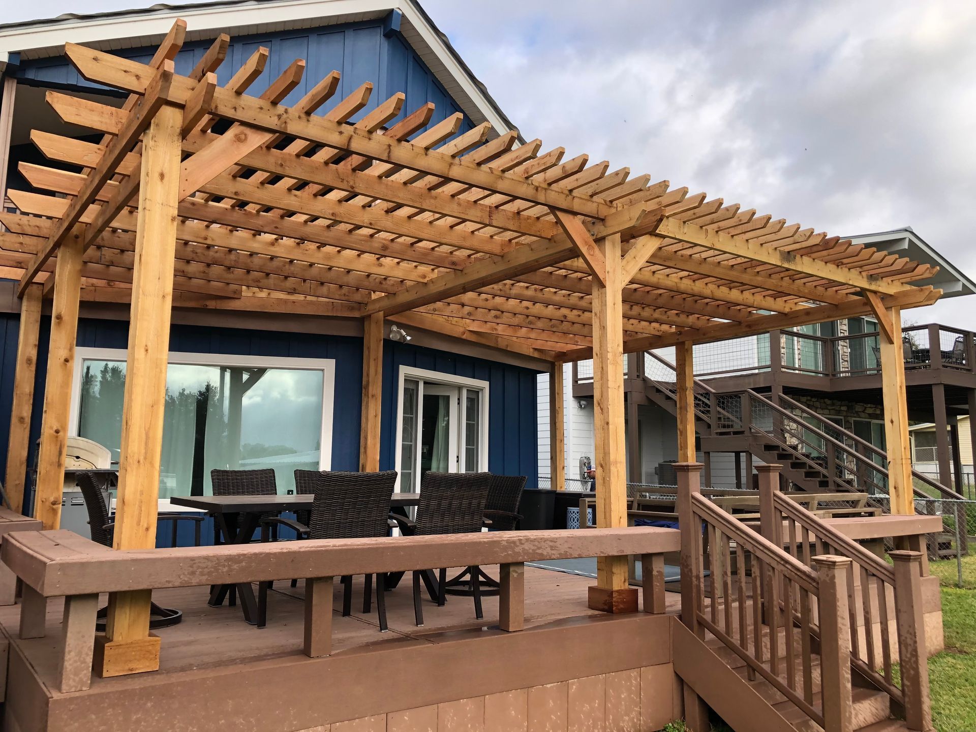 A blue house with a wooden pergola on the deck.