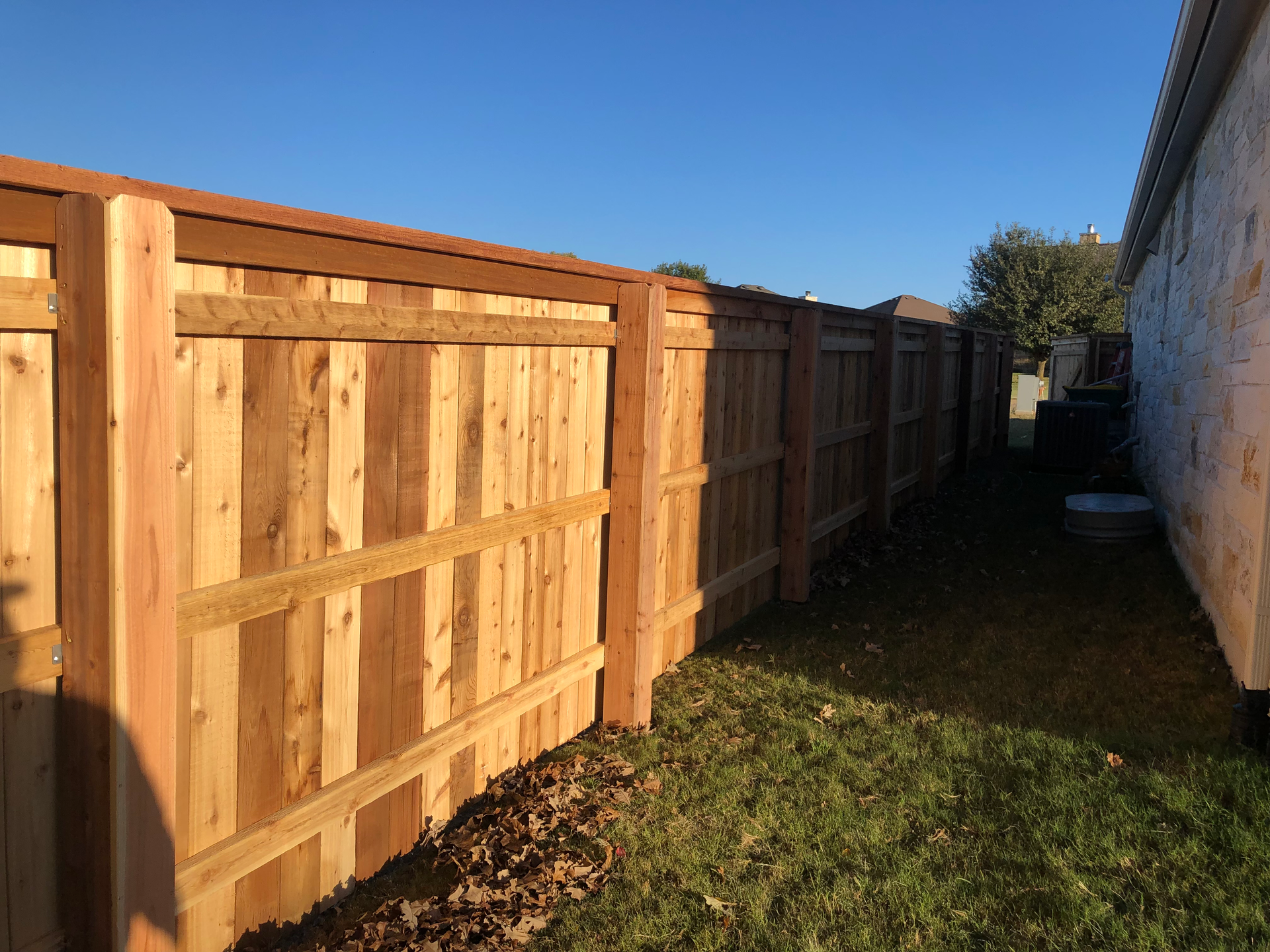 A wooden fence is in the backyard of a house.