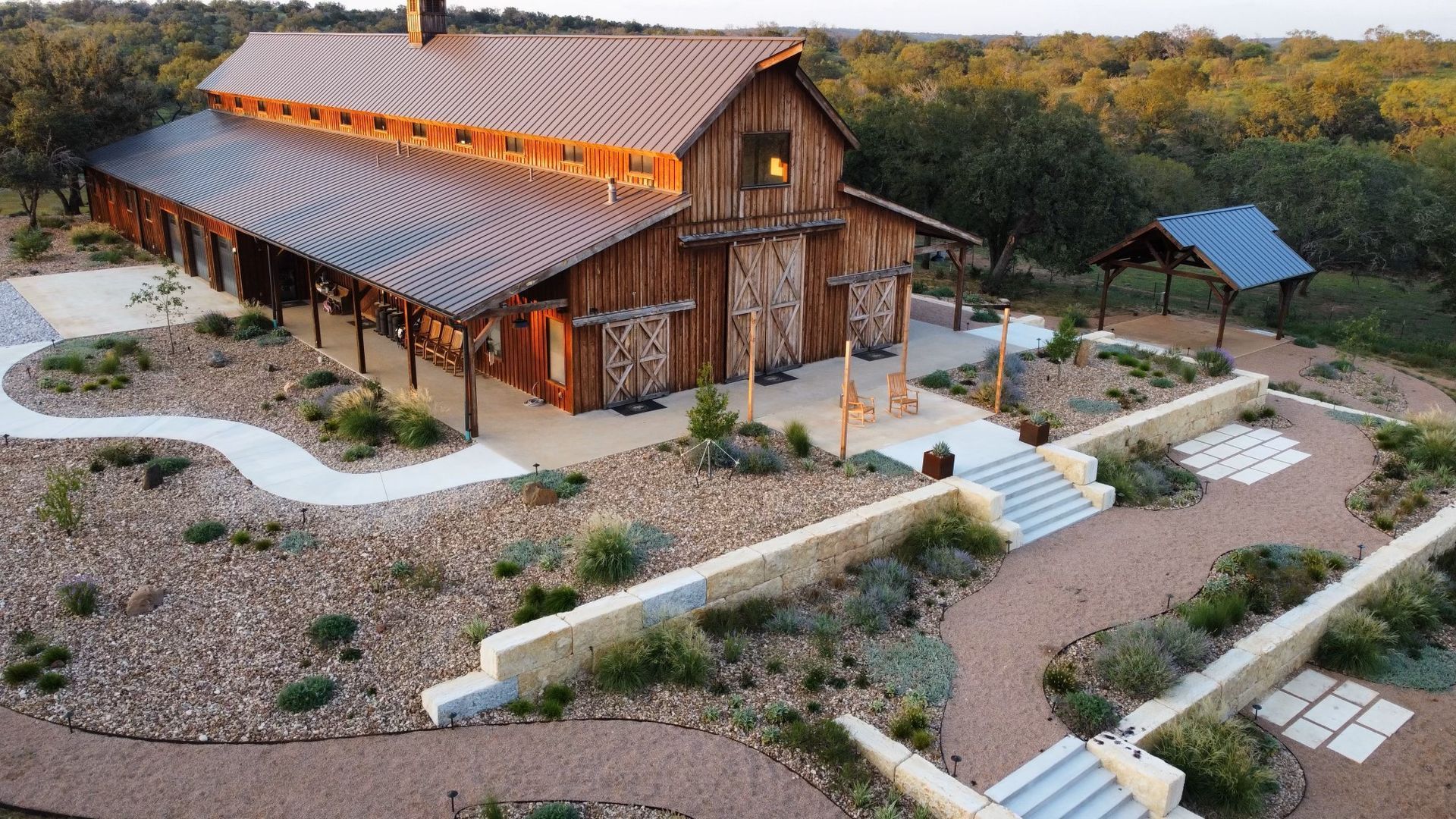 An aerial view of a large wooden barn surrounded by trees.