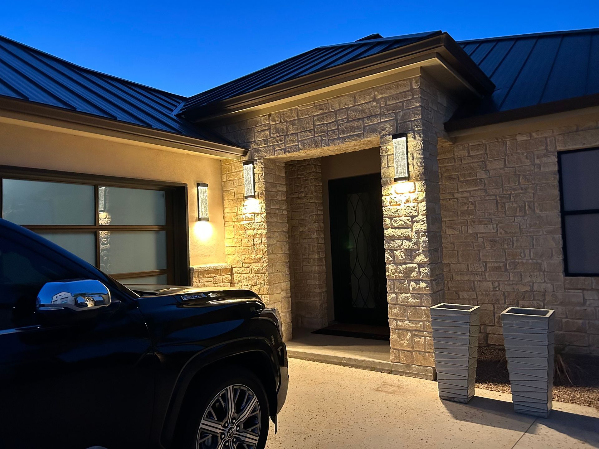 A black truck is parked in front of a brick house