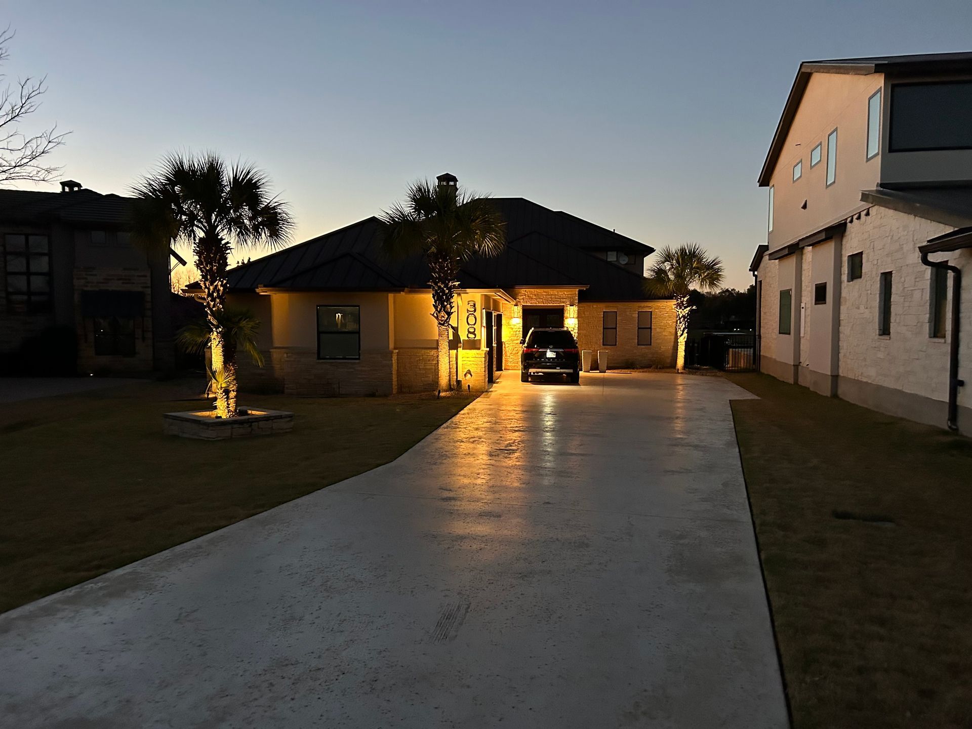 A car is parked in the driveway of a house at night.