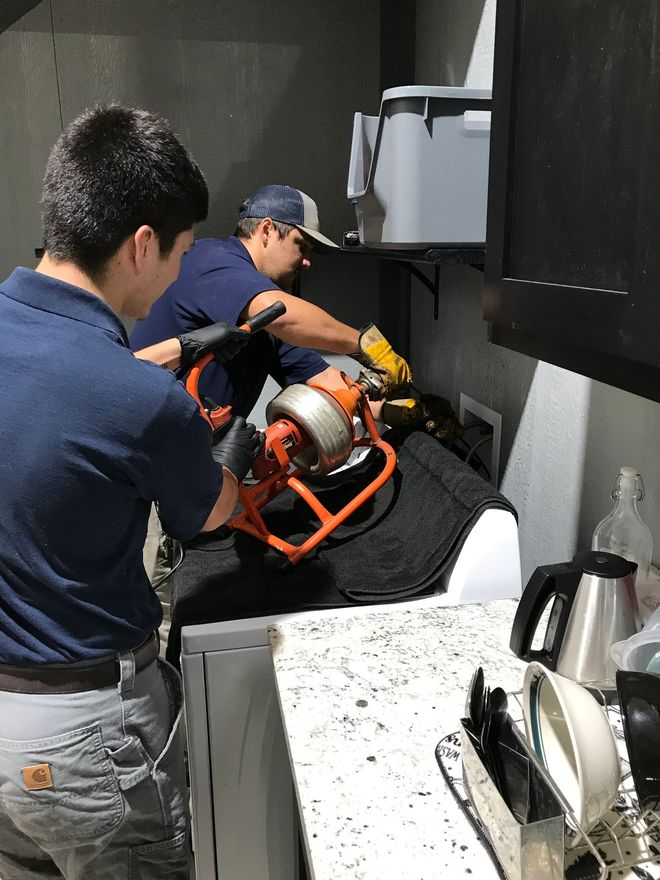Plumbing fittings, including valves and connectors, on a light wood surface.