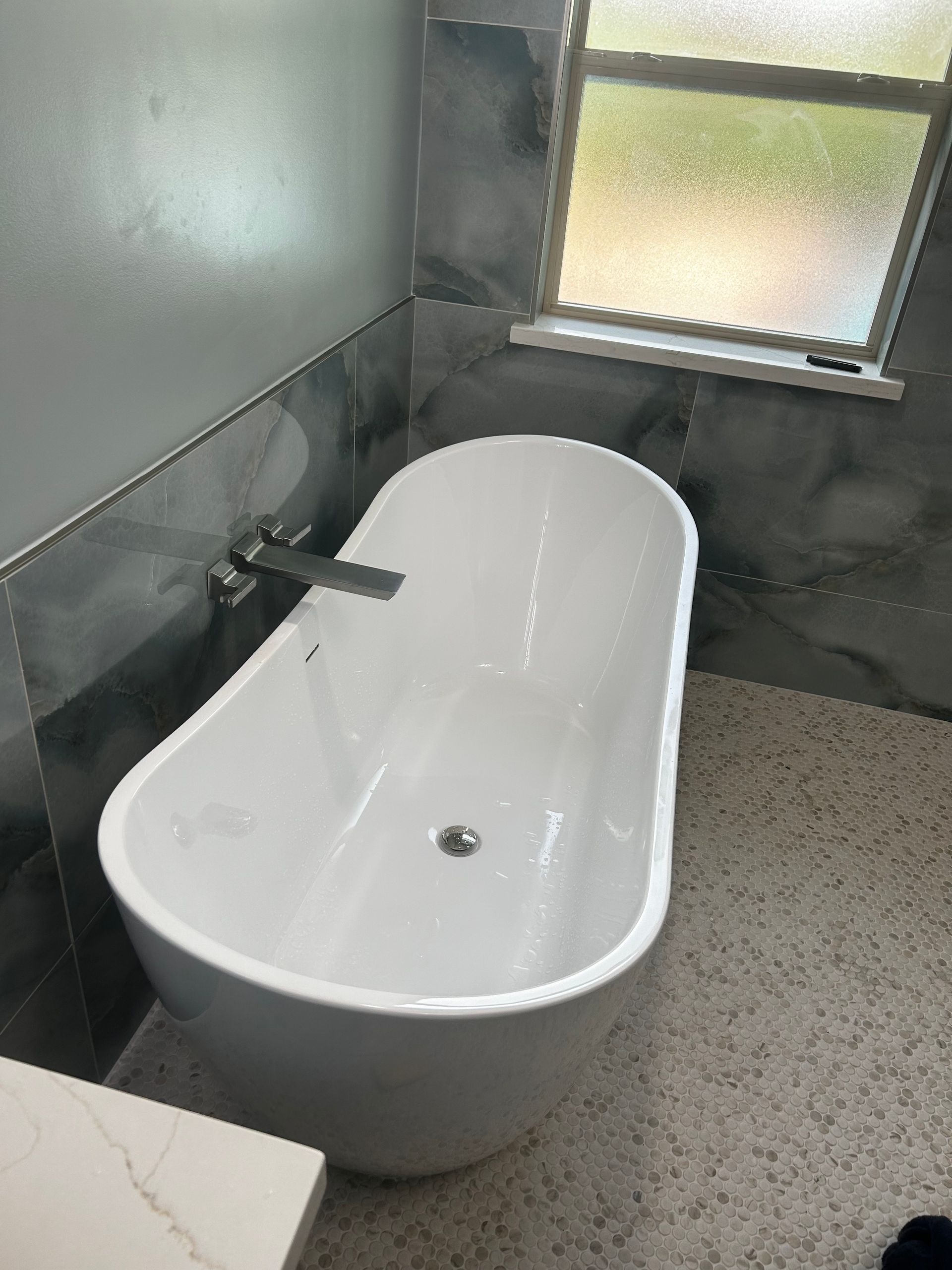 Black and chrome showerhead mounted on a gray tiled wall.