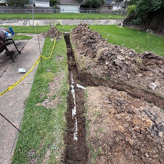 Backyard trench dug beside a grassy path, with piled dirt and yellow caution tape