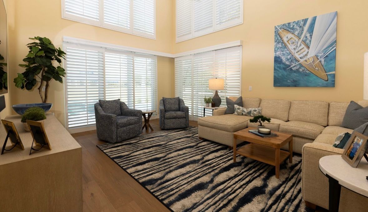 Living room with cream sectional, patterned rug, and sailboat art.