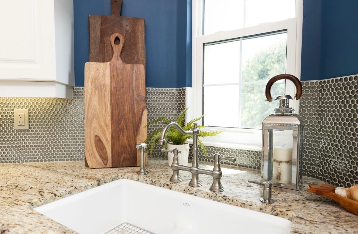 Kitchen sink with granite countertops, a blue wall, and wooden cutting boards.