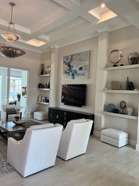 Living room with white chairs, built-in shelves, TV, and blue abstract artwork.
