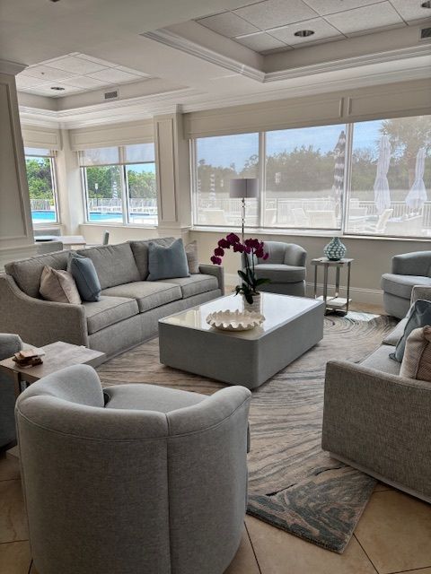 Living room with gray sofas, armchairs, coffee table, and large windows.