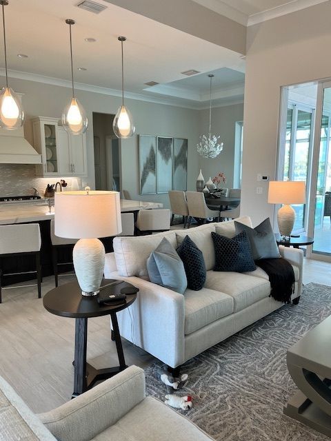 Living room with sofa, lamps, and open kitchen. Neutral tones with blue accents.