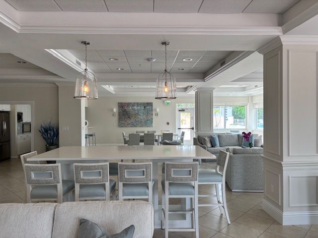 Spacious white-walled interior with a large kitchen island, seating, and two hanging lights.