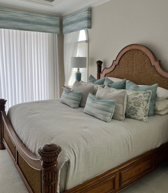 Bedroom with large wooden bed, wicker headboard, blue and white pillows, and light blue valance.
