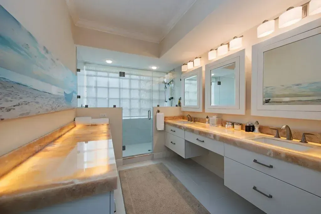 Bright, modern bathroom with double vanity, glass shower, and beach-themed mural.