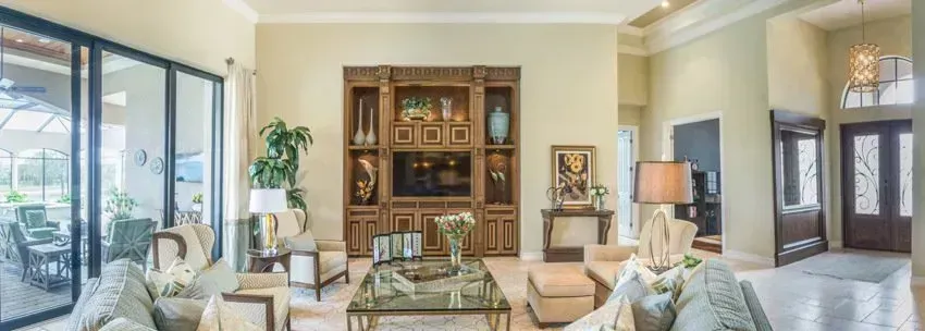Spacious living room with a large wooden entertainment center, glass table, and open doorway.