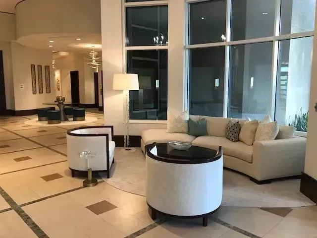 Elegant lobby with white seating, a large window, and a round coffee table.