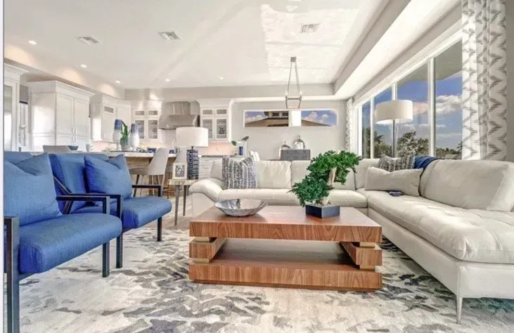 Living room with blue chairs, white couch, and wooden coffee table on a patterned rug.