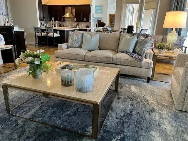 A living room with a couch, coffee table, chairs, and a rug.