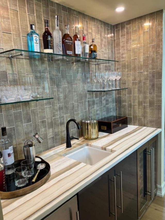 A stylish home bar with liquor bottles, glassware, and a sink.