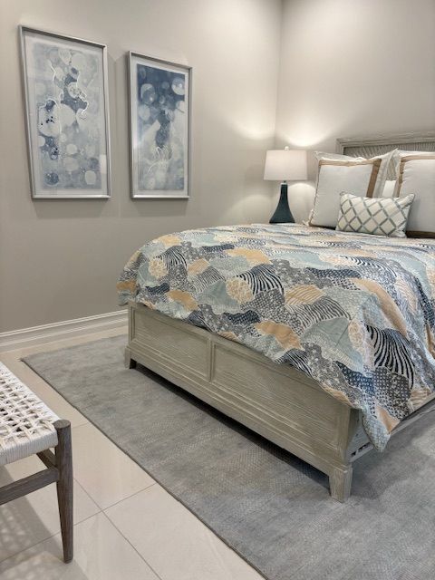 Bedroom with bed, artwork, lamp, and rug, in neutral colors.