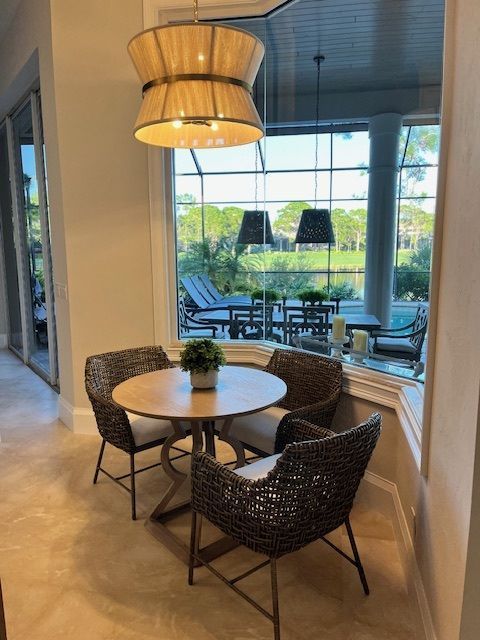 A small dining set inside, with a view of an outdoor patio and golf course.