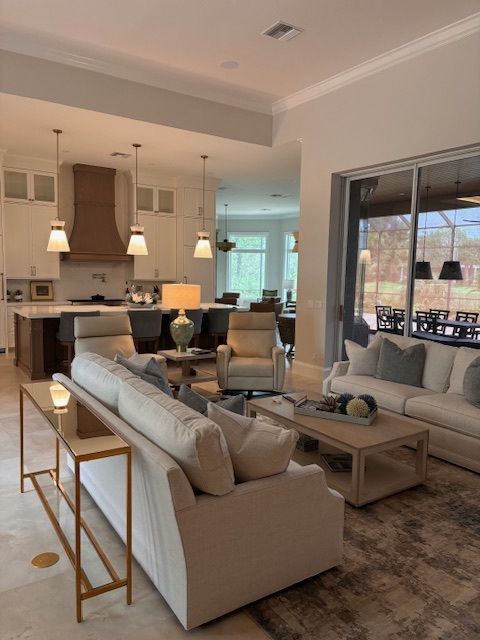 Open-concept living space with kitchen, seating area, neutral colors, pendant lights, and a view of outdoor seating.
