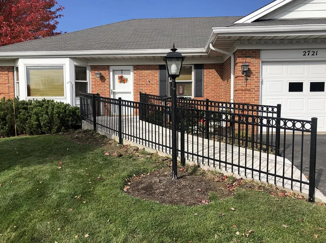 Exterior view of a brick house with a wheelchair ramp and black wrought iron fence.