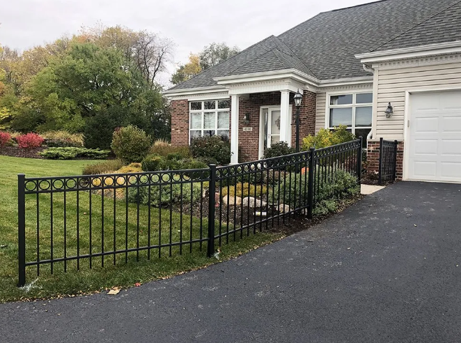 Black metal fence in front of a house with a driveway. Landscaping and a garage are visible.