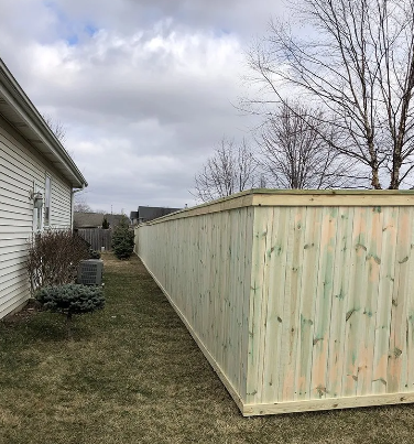 Wooden fence bordering a residential yard; cloudy sky overhead.