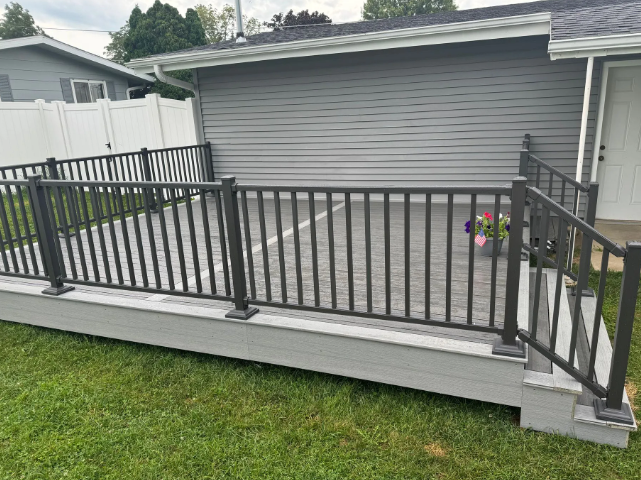 Gray composite deck with black railing and steps against a gray house.