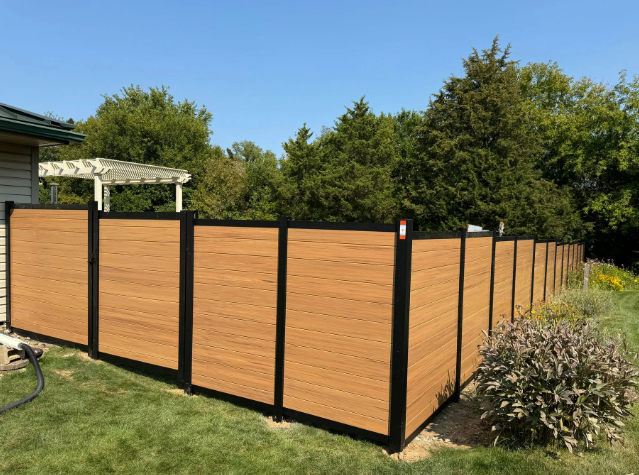 Brown wooden fence with black frames in a sunny yard.