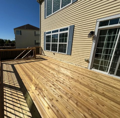 Wooden deck with a house, sliding glass door, and blue shutters.