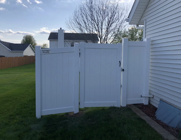 White vinyl fence with gate, set against a house and lawn, providing a private enclosure.