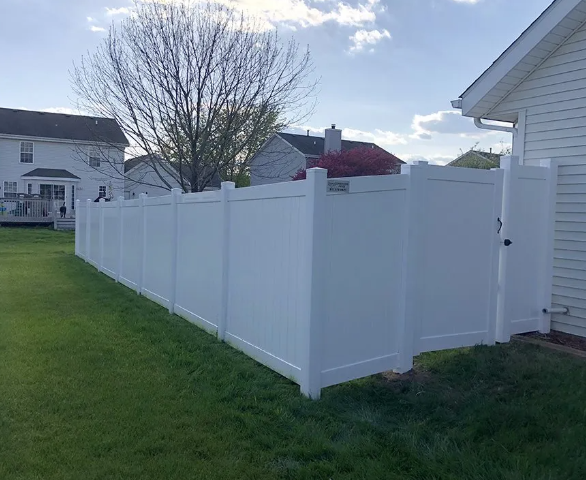 White vinyl privacy fence with gate in residential backyard.
