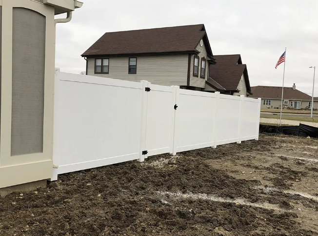 White privacy fence with a gate in front of a house.