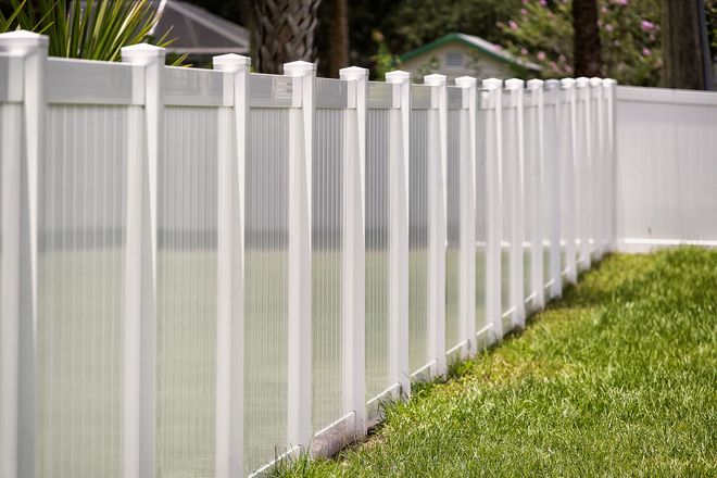 White vinyl fence bordering a green lawn.