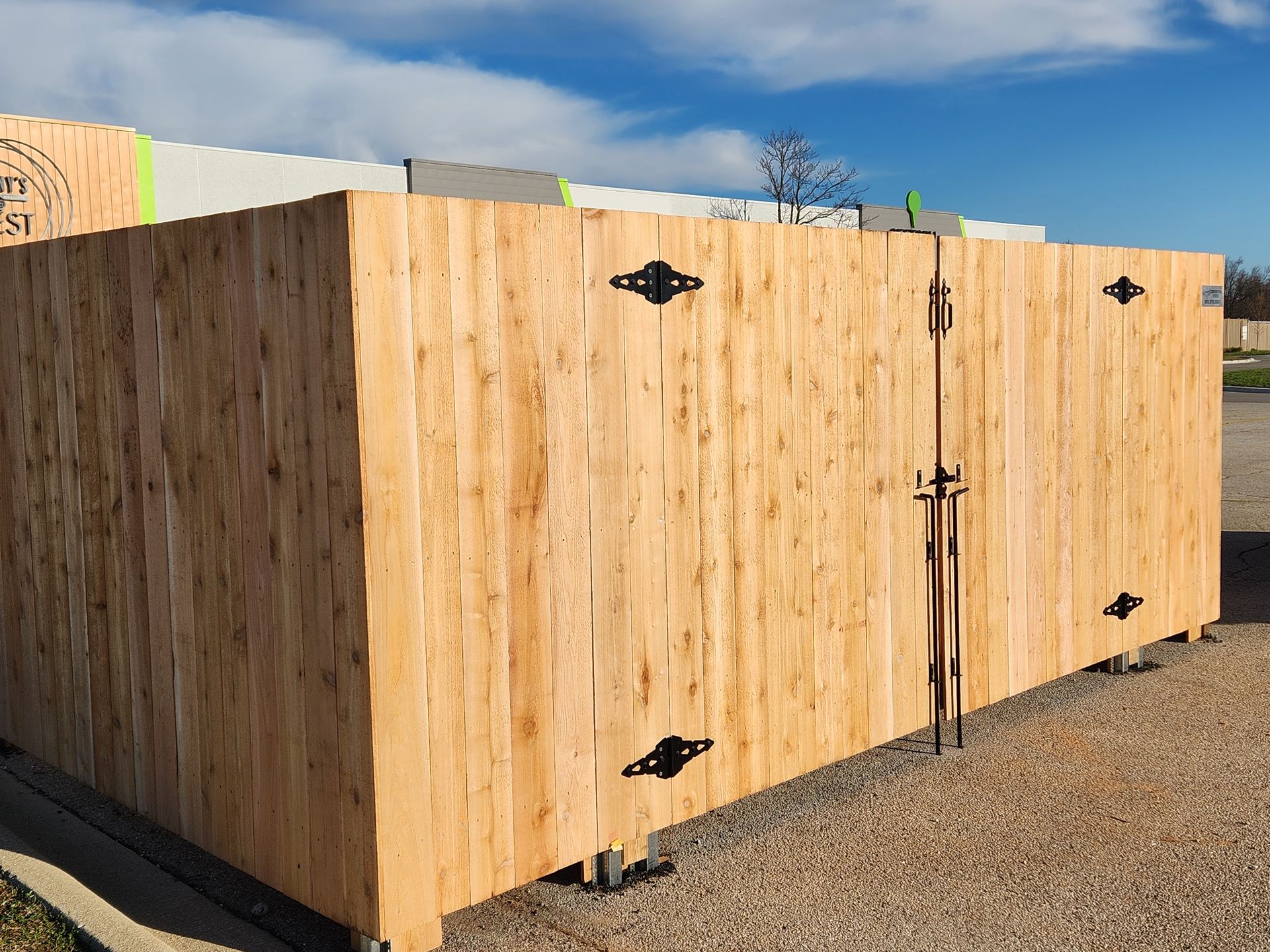 Wooden crate with metal hinges and latch, outdoors on gravel, against a blue sky.