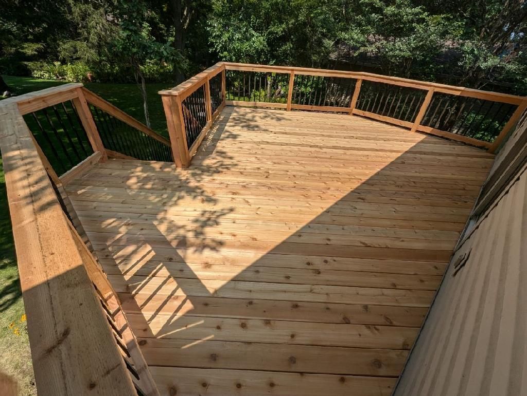 Wooden deck with railings, steps, and surrounding greenery.